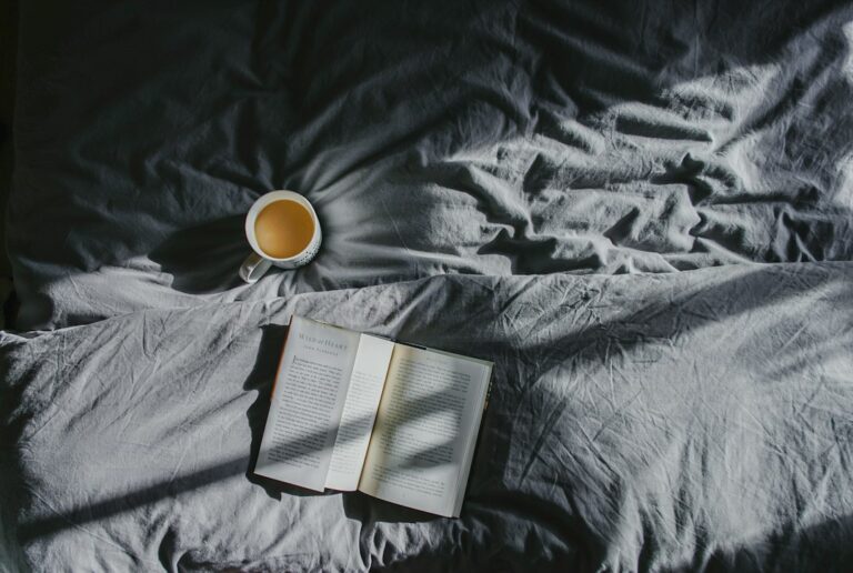 A cup of tea and an open book beside a window, representing a calm and repeatable daily habit.