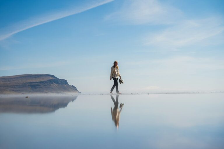 A person walking alone across shallow water, representing following your own path instead of comparing yourself with others.