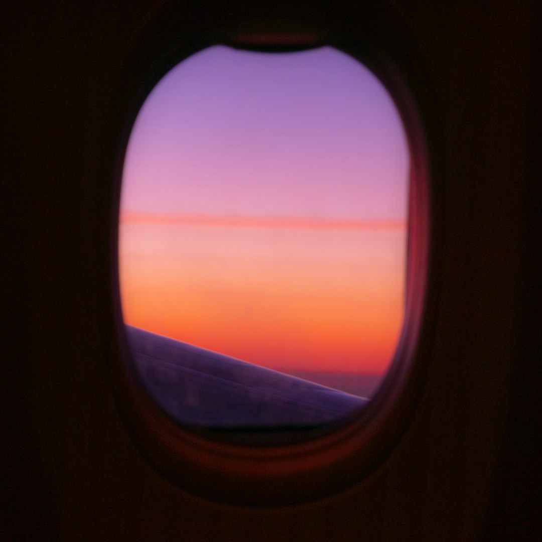 A warm sunset seen through an airplane window. Photograph by Nils Mahler on Unsplash.